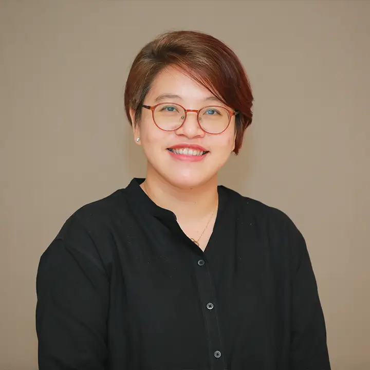 headshot of a smiling young Burmese woman with short brown hair and glasses